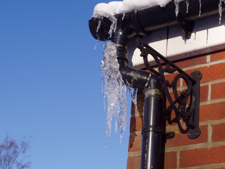 Frozen pipe with icicles hanging from a home's exterior.