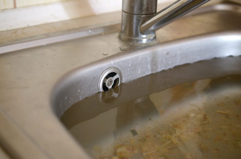 Kitchen sink overflowing with dirty water.