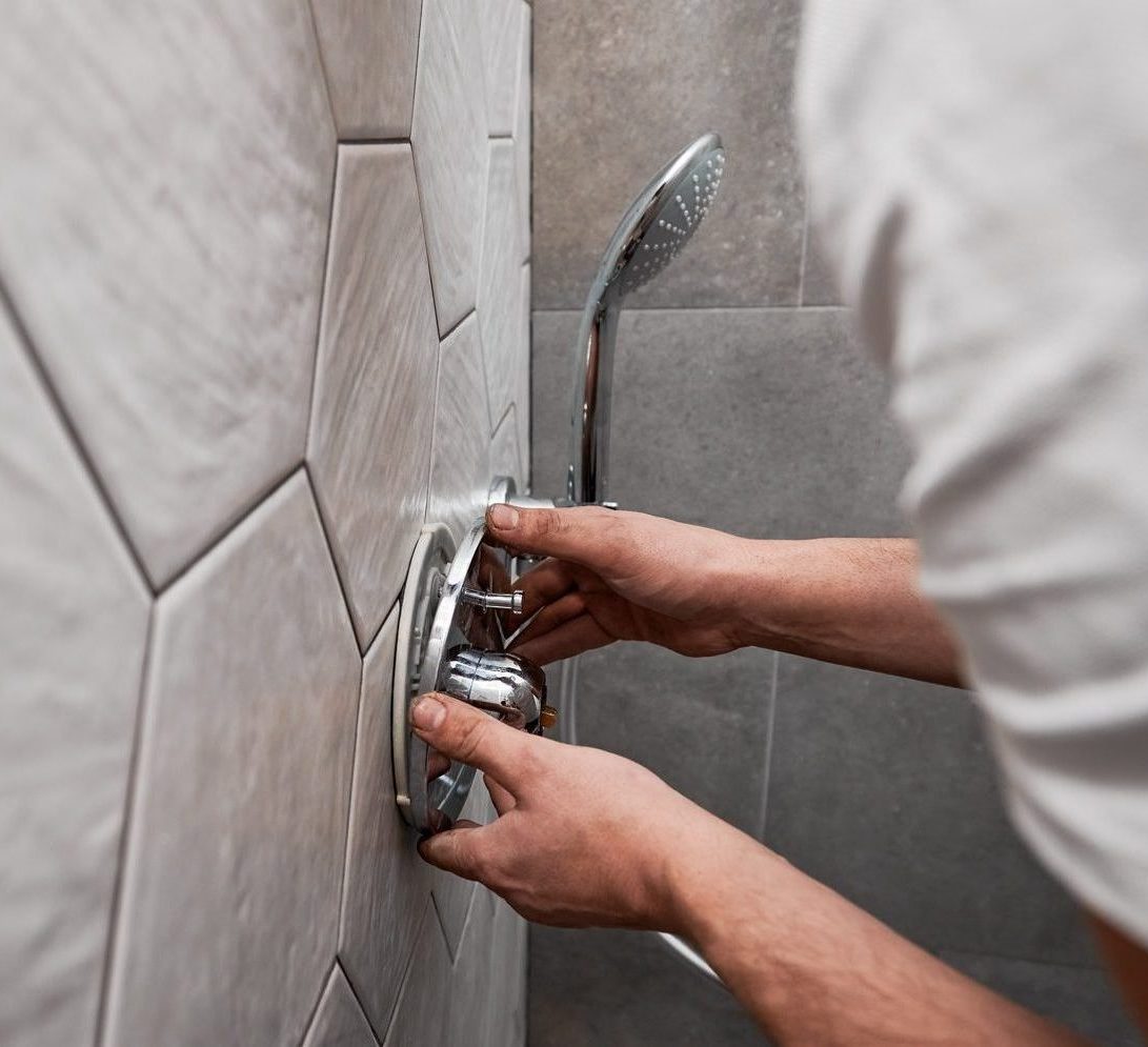 Plumber installing a shower head as part of a plumbing service.