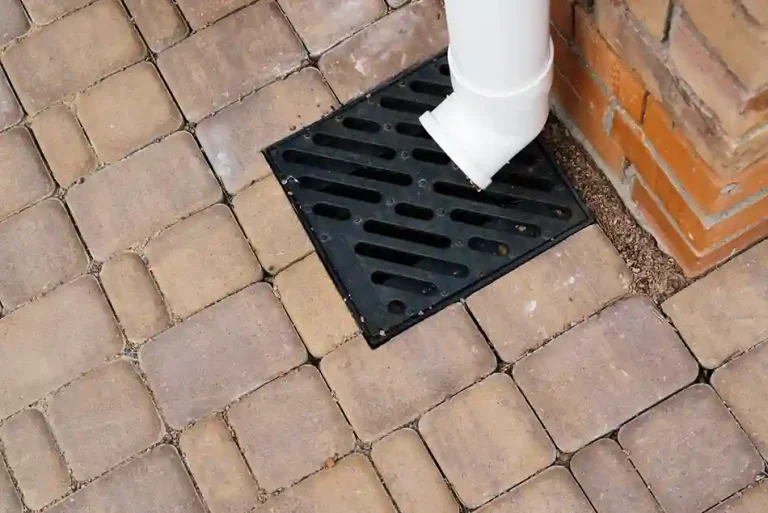 Cast iron stormwater drainage grate installed in pavement.