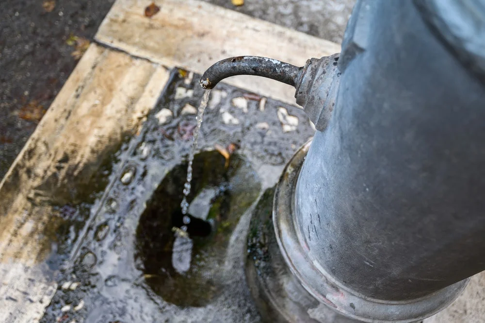 Close-up of a corroded plumbing pipe fitting leaking water, illustrating a common pipe leak repair issue in Spokane, WA homes.